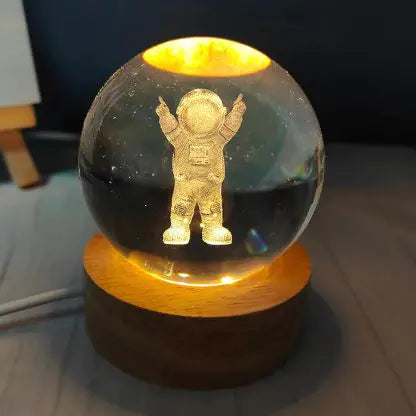 A USB crystal ball night light glowing with a warm light, resembling a birthday cake with candles on top, placed on a wooden surface.