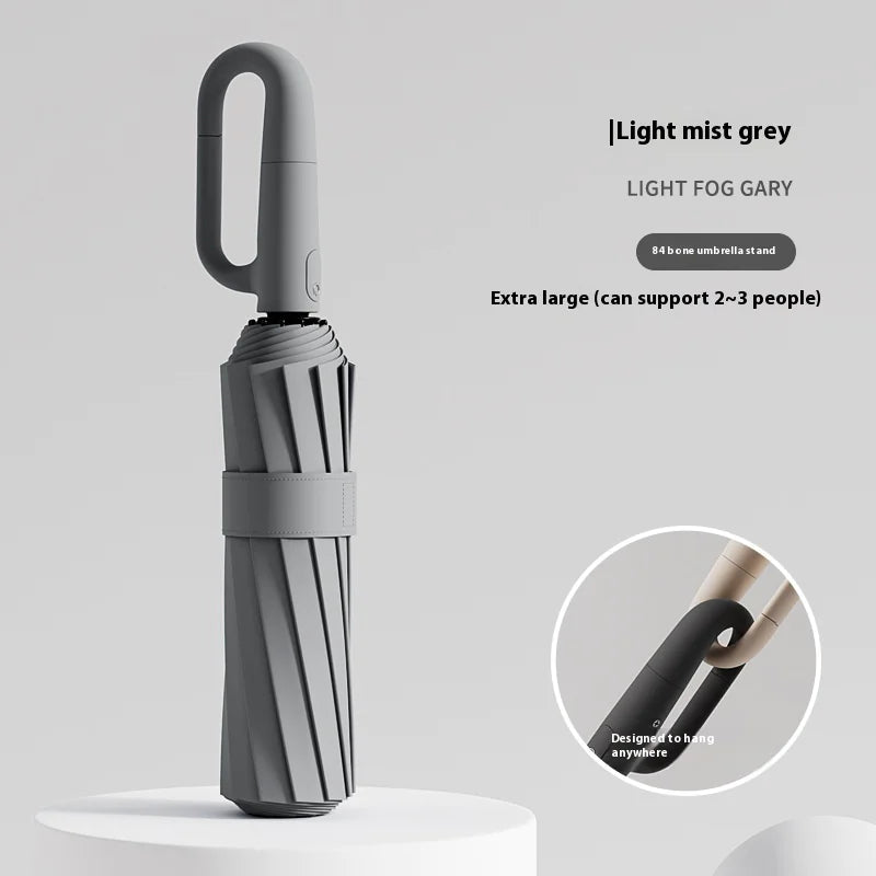 A white umbrella with a ring buckle, standing on a white surface, with a close-up inset showing the texture of the umbrella's fabric.