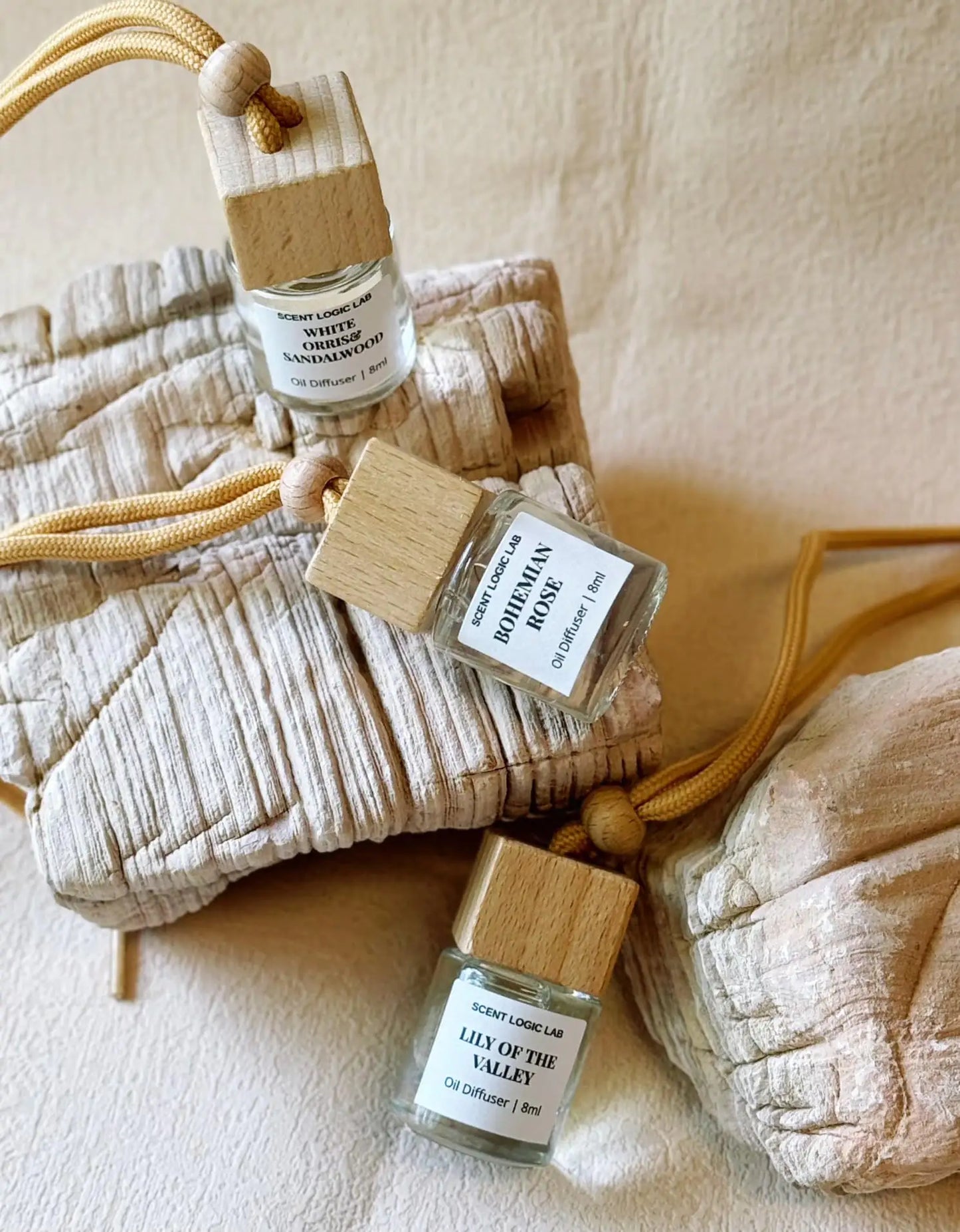 A set of holiday scented diffusers designed for use in cars, with glass bottles, wooden blocks, and labels, displayed on a neutral background.