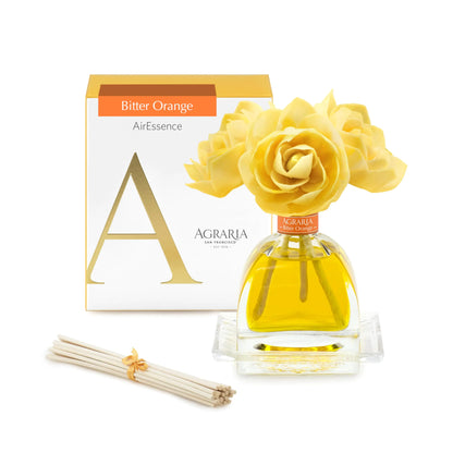 Agraria PetiteEssence room fragrance diffuser set with a handcrafted sola flower and reed sticks in a blue box decorated with red leaves and a red ribbon.
