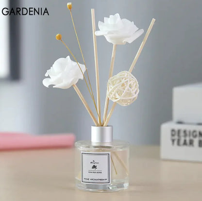 A glass aromatherapy bottle with a white label, filled with water-based essential oils and adorned with white floral rattan sticks.