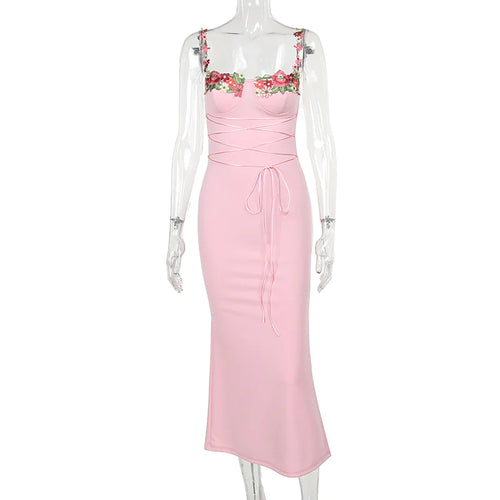 A pink sleeveless knee-length dress with floral decal accents at the chest and waist girdling feature.