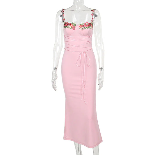 A pink sleeveless knee-length dress with floral decal accents at the chest and waist girdling feature.