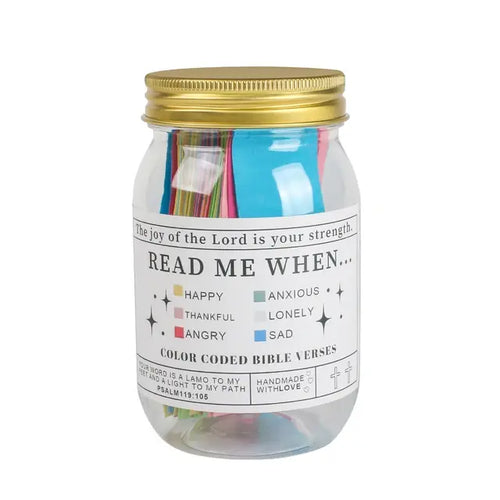 A glass jar with a gold lid containing colorful paper strips with Bible verses, labeled with different emotions such as 'Happy', 'Anxious', 'Thankful', 'Angry', 'Lonely', 'Sad'. The label 'READ ME WHEN.