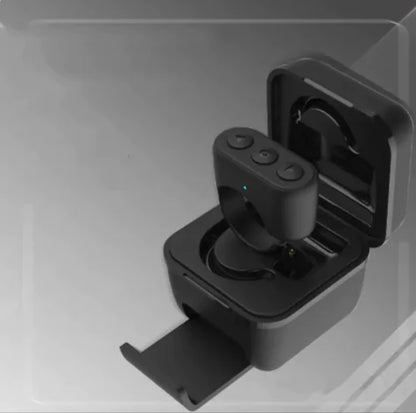 A Bluetooth fingertip remote placed inside its charging case, which is open and showing the remote's battery level indicator.