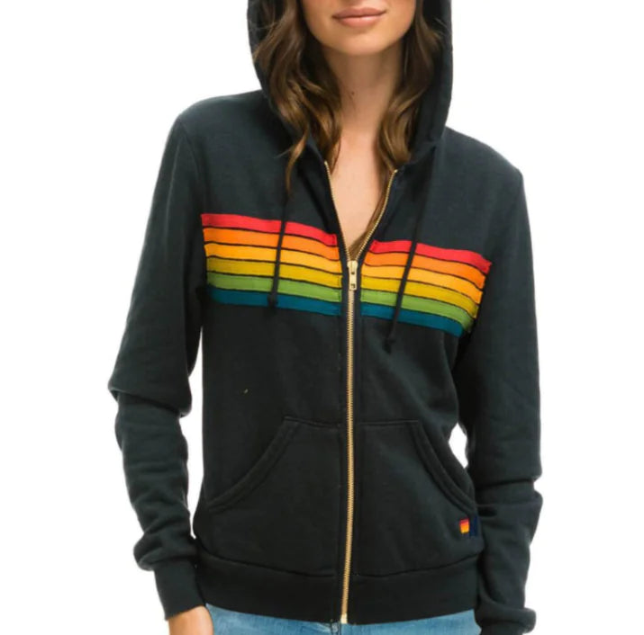 A woman wearing a black zip-up hoodie with vibrant multicolor stripes on the front.