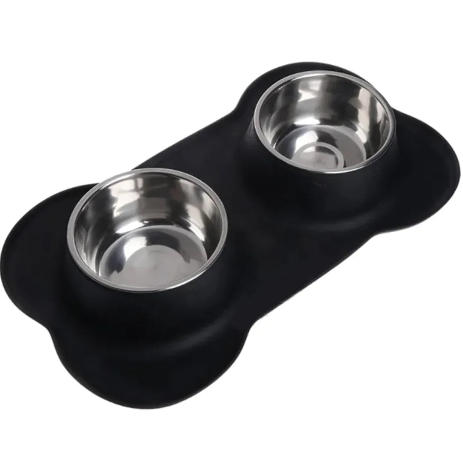 A black silicone pet bowl mat in a bone shape, with two stainless steel bowls placed on it.
