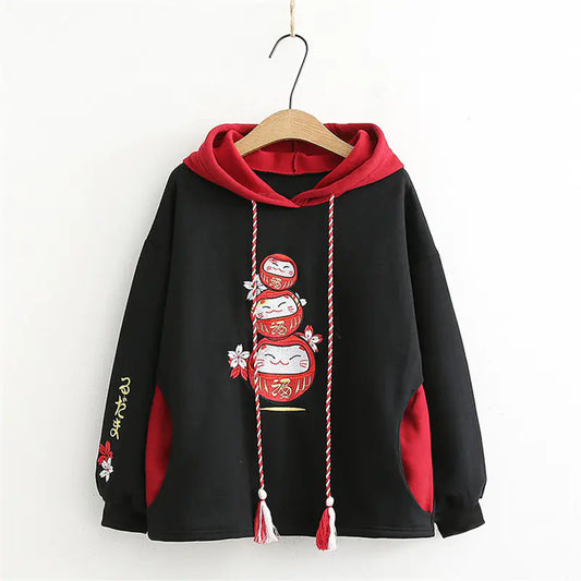 A black hooded velvet sweater with red embroidery featuring a cartoon design, displayed on a mannequin.