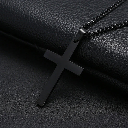 A black cross necklace made of stainless steel, displayed against a black leather background.
