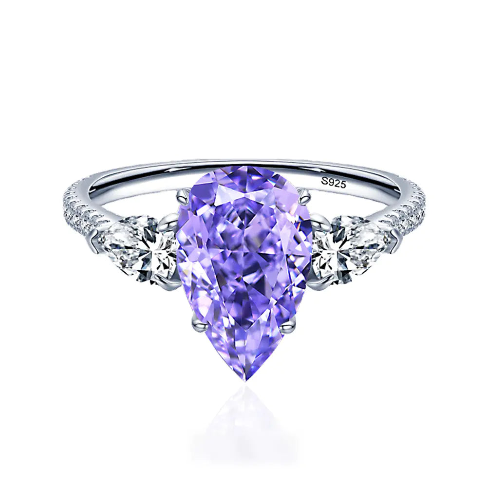 A sterling silver ring with a drop-shaped purple diamond centerpiece and accent diamonds around it.