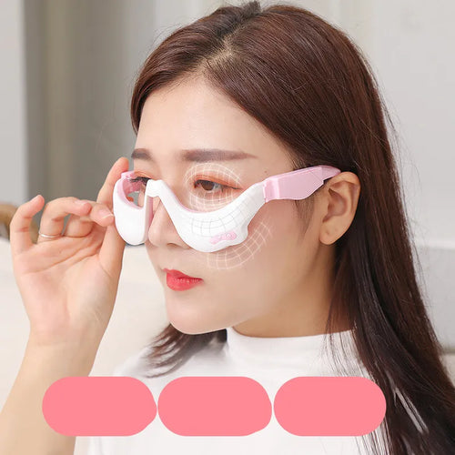 A person demonstrating the use of an electric eye bag massager on their face, with the device visible as a pair of pink and white goggles.
