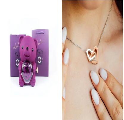 A teddy bear gift box in blue with a preserved rose and a necklace, alongside a rotating rose jewelry box, against a white background.