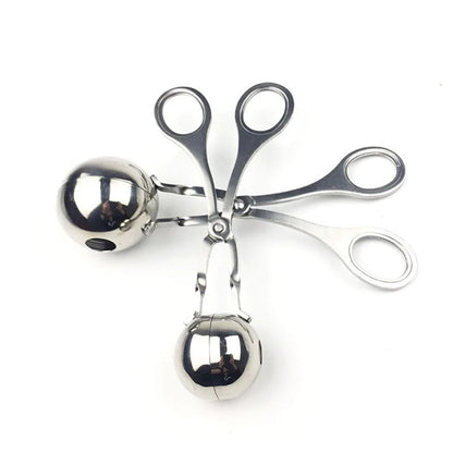 Metallic scissors with two hanging metallic balls on a white background
