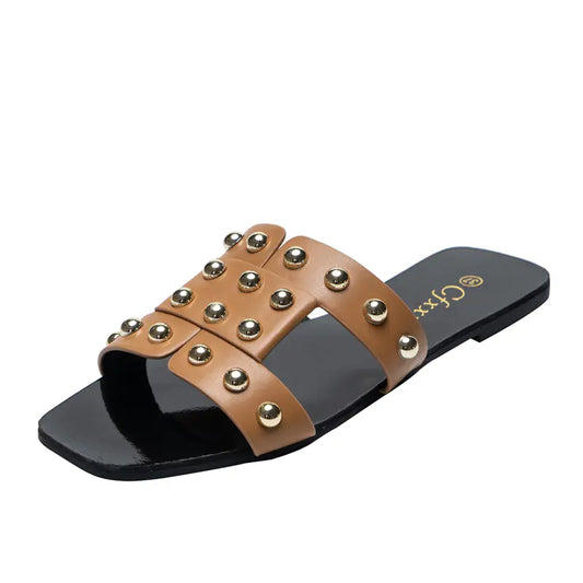 A pair of brown flat sandals with metal rivet accents on a black rubber sole, designed for women's casual wear.