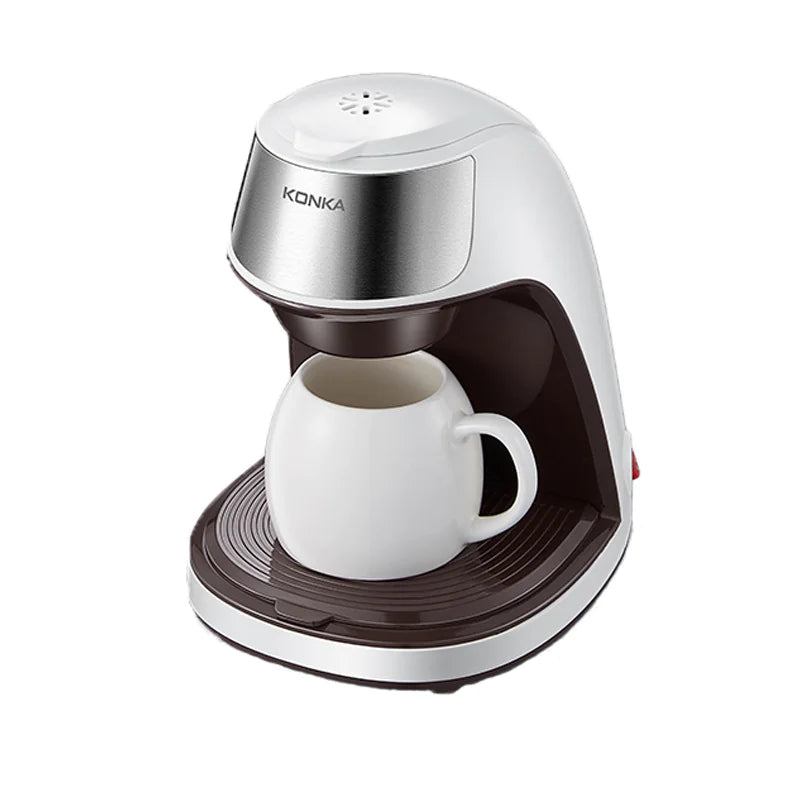 A compact, fully automatic mini coffee machine with a white ceramic cup placed under the spout. The coffee machine has a silver and brown color scheme.