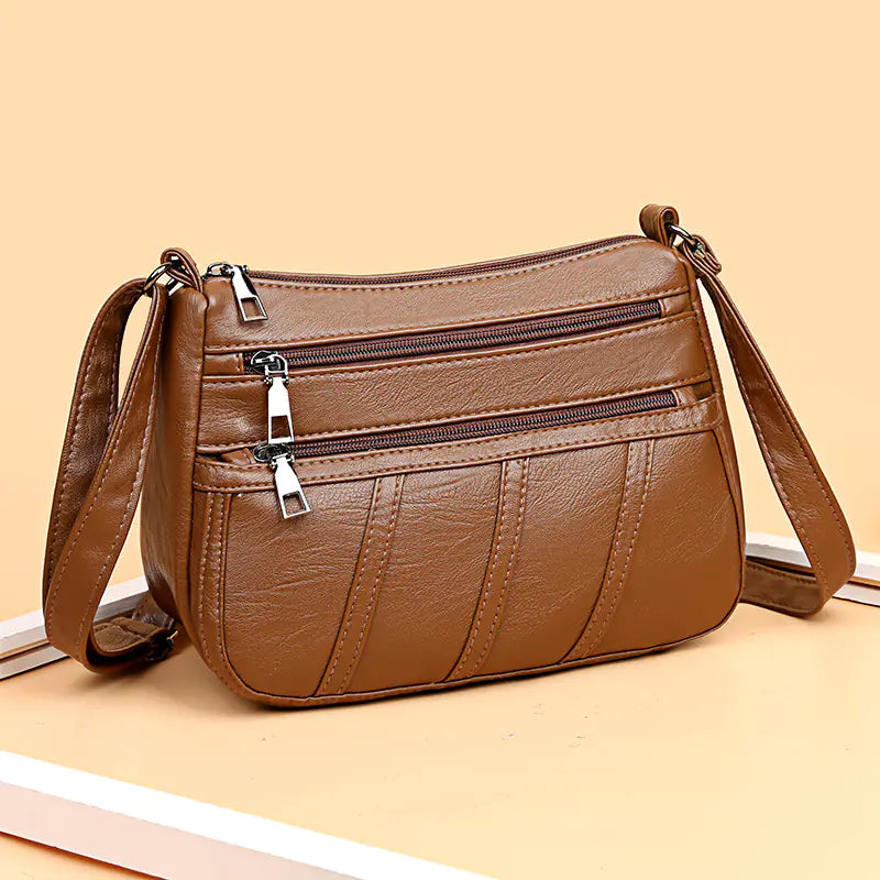 A brown faux leather shoulder bag with multiple compartments and a solid pattern.