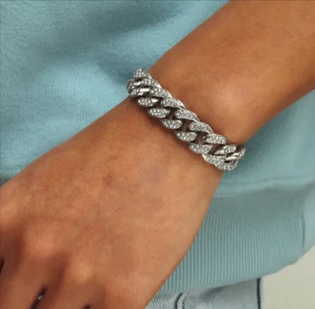 A man's wrist wearing a silver rhinestone bracelet with a floral design.