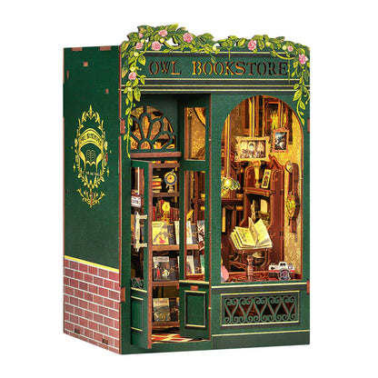 A miniature DIY cottage book stand designed as an assembled model, featuring a green exterior with bookshelves and a sign reading 'Owl Bookstore'.