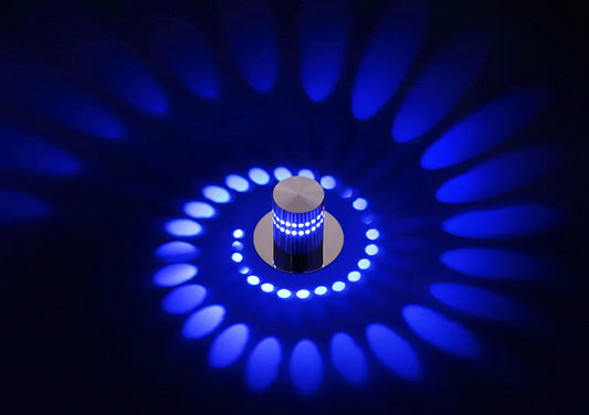 A modern LED color-changing wall light fixture installed on a ceiling, surrounded by a circular pattern of blue light.