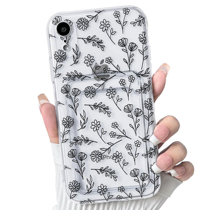 A hand holding a clear iPhone case with a floral leave pattern