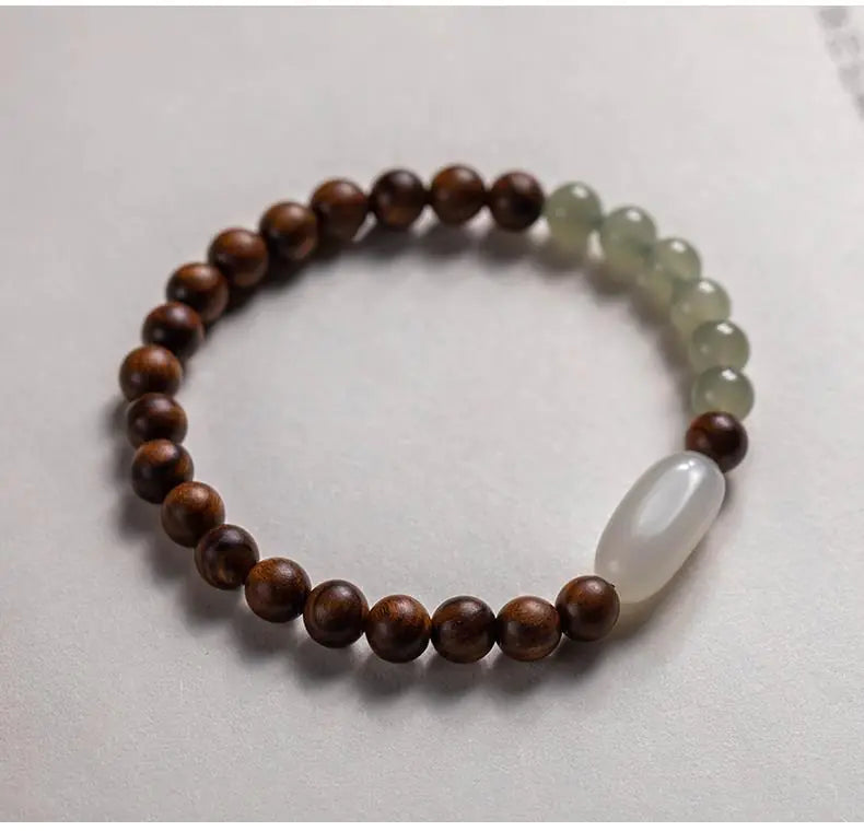 A two-tone bracelet with round beads, featuring nanmu hand string and Hetian jade, displayed against a light background.