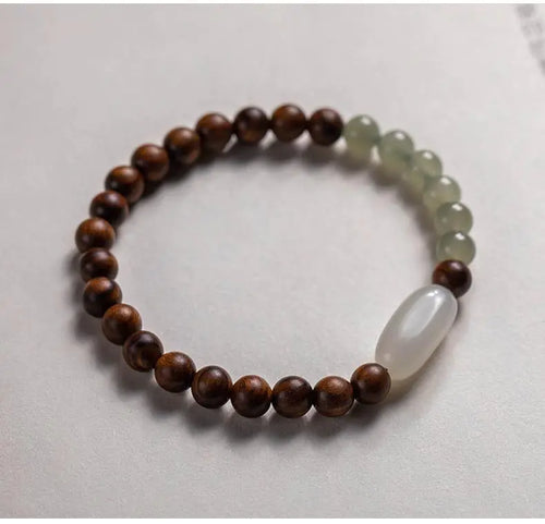 A two-tone bracelet with round beads, featuring nanmu hand string and Hetian jade, displayed against a light background.