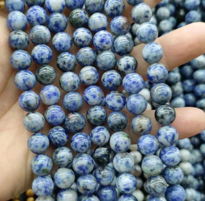 A hand holding round beads with a mix of blue and white colors, part of the Natural Tiger Stone Powder with Amethyst and Lapis collection.