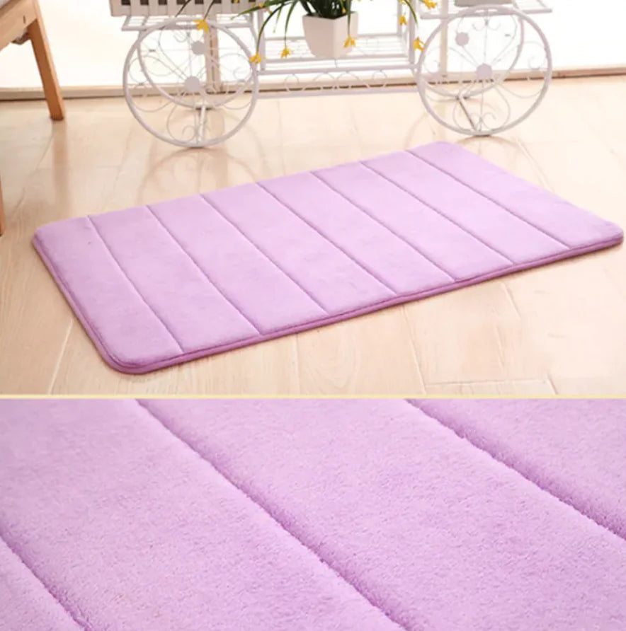 A rectangular purple floor mat with a grid pattern, placed on a floor with a bicycle and table in the background.