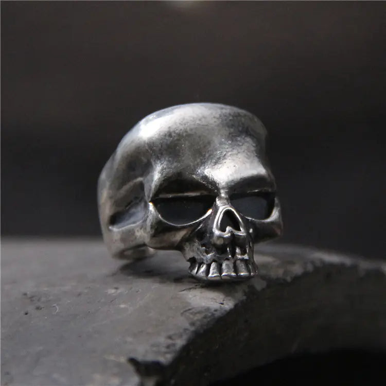 A silver sterling skull ring with an open buckle design on a textured background.