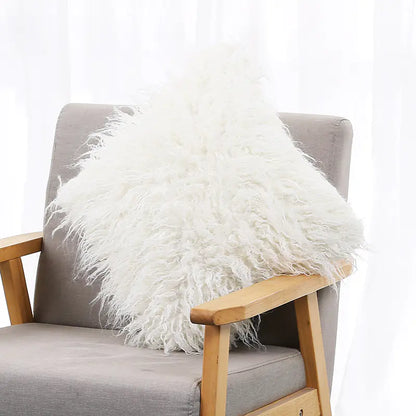 A white plush cushion cover with a long wool-like texture, displayed on a gray armchair.