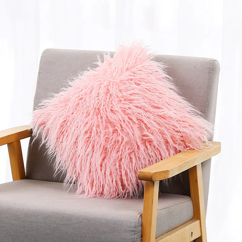 A white plush cushion cover with a long wool-like texture, displayed on a gray armchair.
