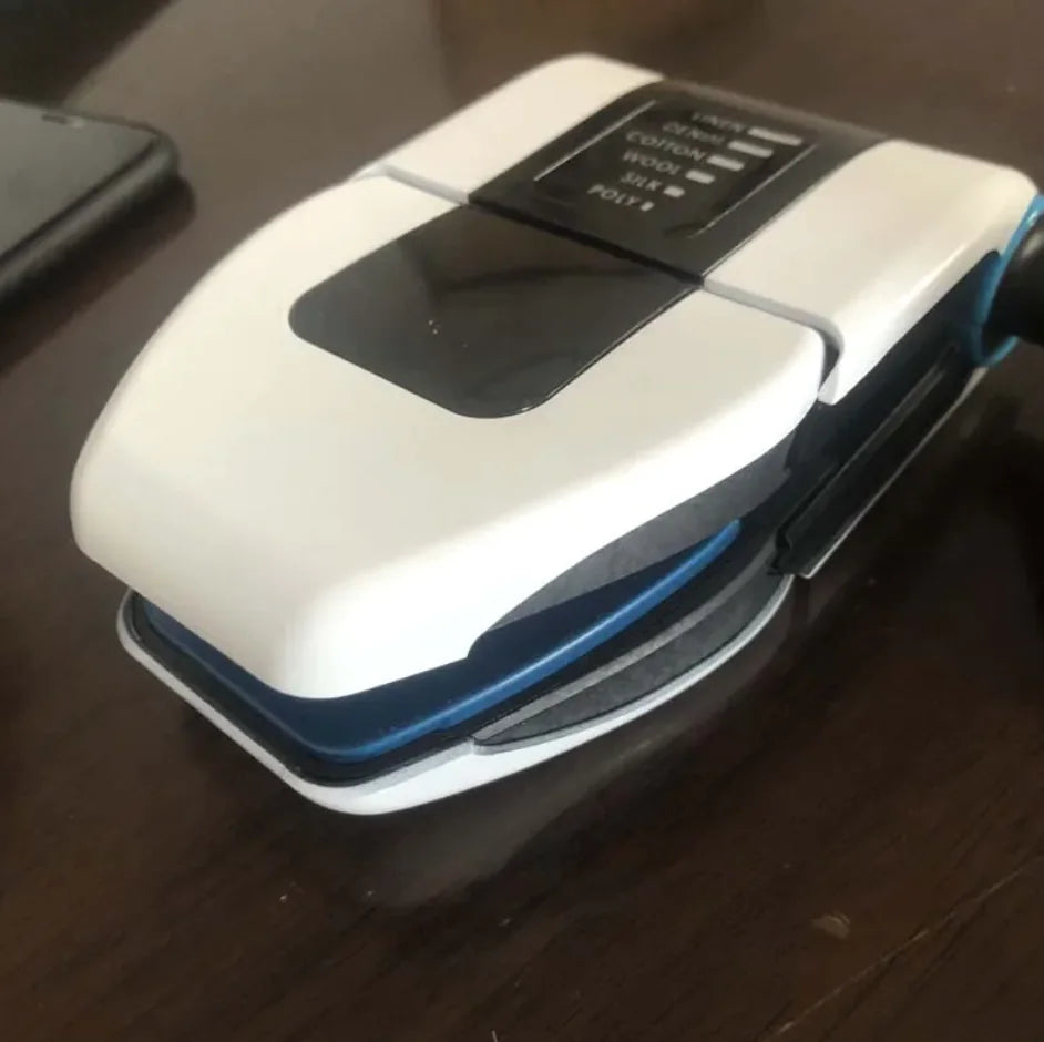 A portable foldable electric iron being used to iron a blue striped shirt.