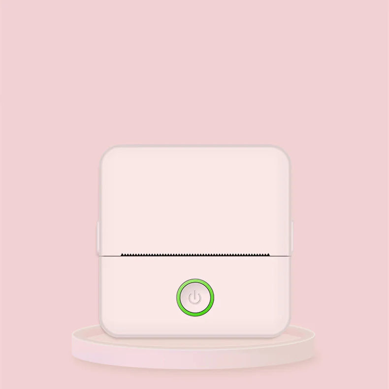 A compact portable thermal printer with a white body and a green power button, displayed against a pink background.