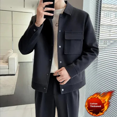 A person wearing a black premium short woolen overcoat with a classic button closure and side pockets. The coat has a regular sleeve length and long sleeve, and the person is also wearing a beige sweater.