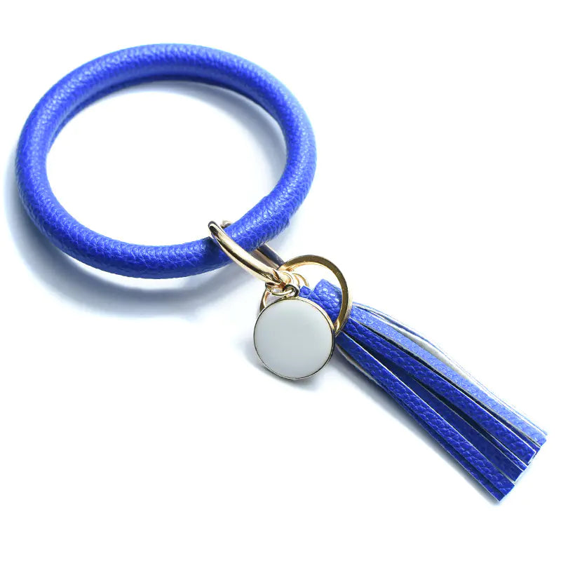 A hand holding a pure leather tassel pendant bracelet with a keyring attached, featuring a zebra-like print.