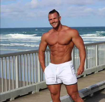 A man wearing green QuickFit sports shorts, showcasing his muscular physique.