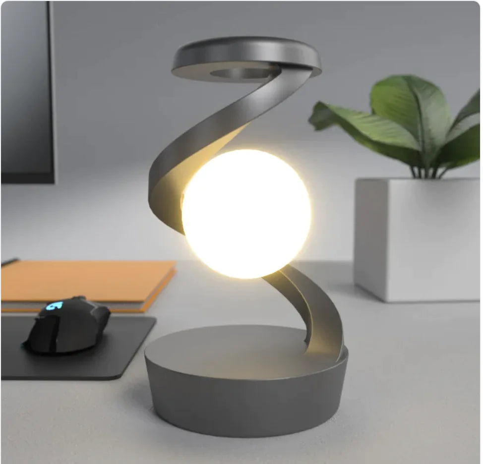 A modern, minimalist desk lamp with a unique rotating moon design, emitting a soft white light, placed on a marble surface.