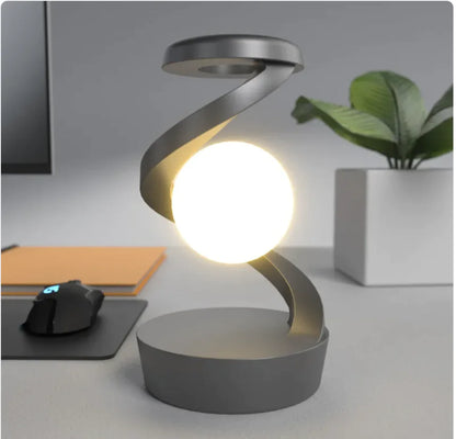 A modern, minimalist desk lamp with a unique rotating moon design, emitting a soft white light, placed on a marble surface.