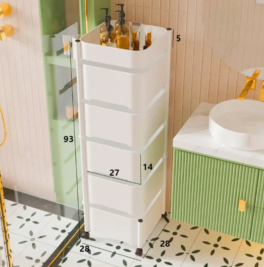 A black rotating snack storage rack with dimensions labeled on the image, placed on a wooden floor next to a bed with a yellow lamp on top.