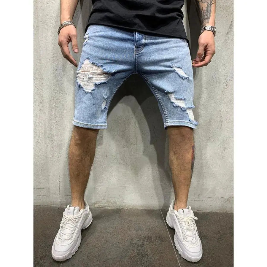A pair of men's slim fit denim shorts with holes, worn with a black top and white sneakers.