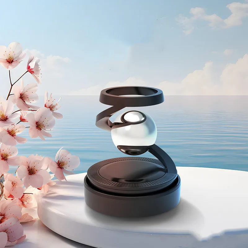 A solar car aromatherapy perfume diffuser positioned on a surface with a backdrop of a clear sky and cherry blossoms.