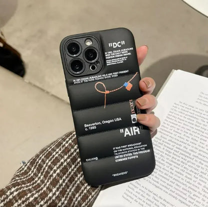 A black iPhone case with text and a graphic design, held in a person's hand.