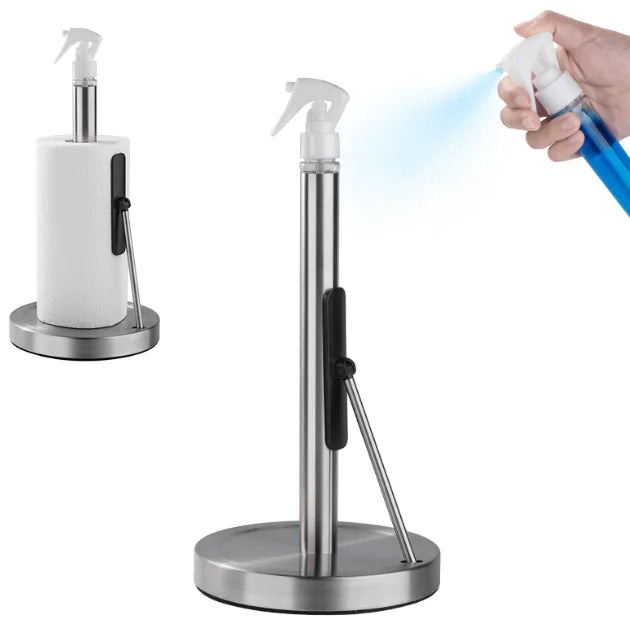 A stainless steel tissue and towel holder with a vertical design, featuring a paper towel roll mounted on top and a spray bottle being used to dispense a liquid.