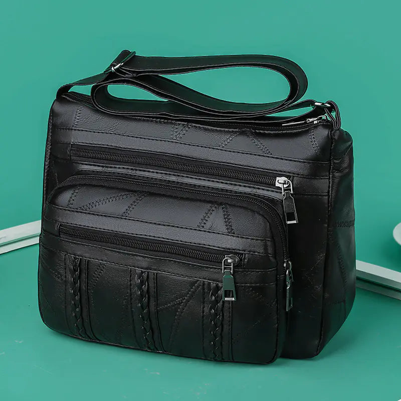 A brown faux leather shoulder bag with multiple compartments and a solid pattern.