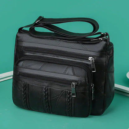 A brown faux leather shoulder bag with multiple compartments and a solid pattern.