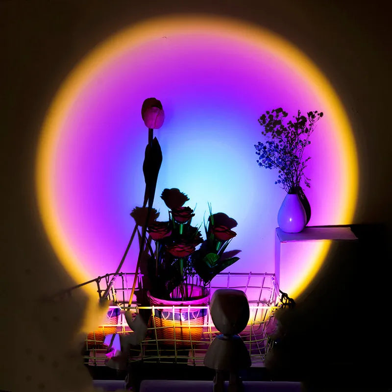 A sunset night light atmosphere lamp with a projection of a golden sunset on a wall, featuring an astronaut figure and illuminating a shelf with flowers and a microphone.