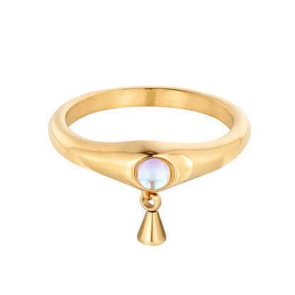 A gold-colored titanium steel ring with a pearl-like embellishment on a blue background.