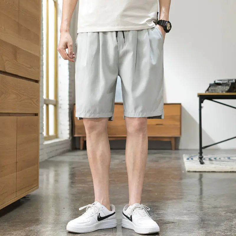 A person wearing beige Korean style five-point pants with a middle waist and a tether closure, paired with a white t-shirt and white sneakers.
