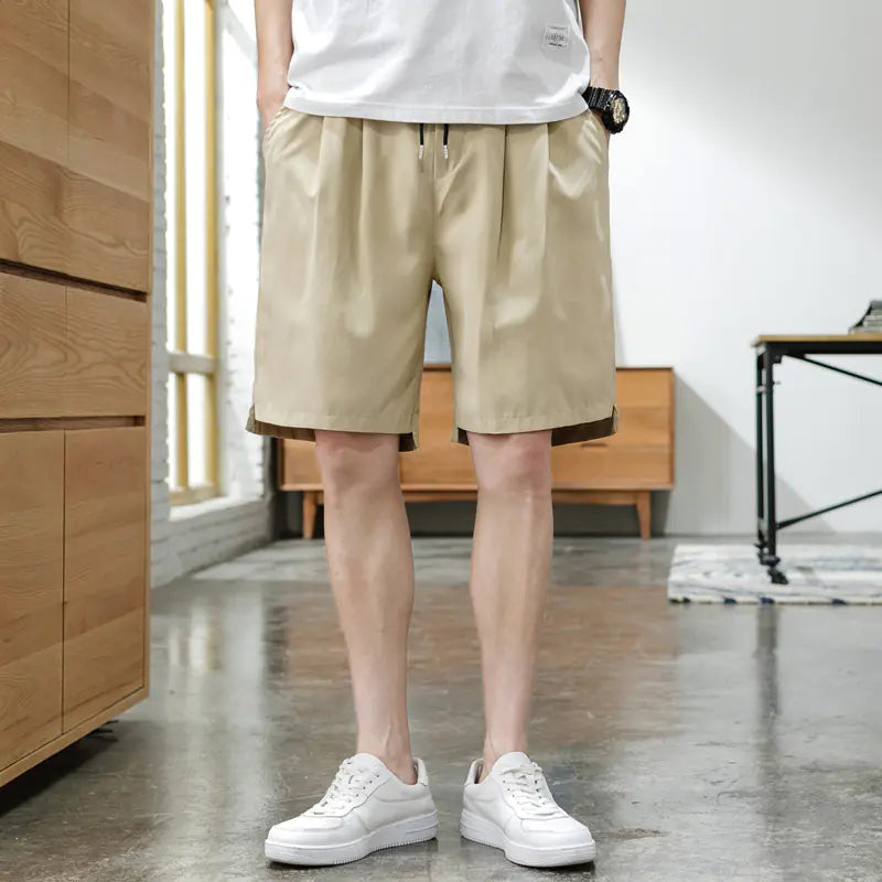 A person wearing beige Korean style five-point pants with a middle waist and a tether closure, paired with a white t-shirt and white sneakers.