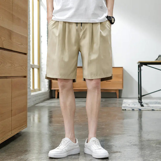 A person wearing beige Korean style five-point pants with a middle waist and a tether closure, paired with a white t-shirt and white sneakers.